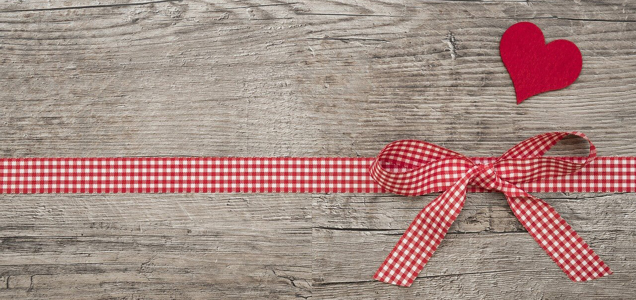 Red ribbon and heart on wood background